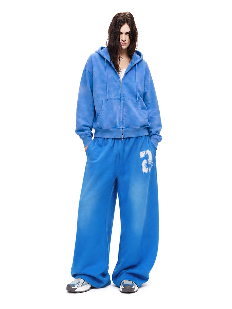 Full-body shot of a model wearing a bright blue hoodie and matching wide-leg track pants.