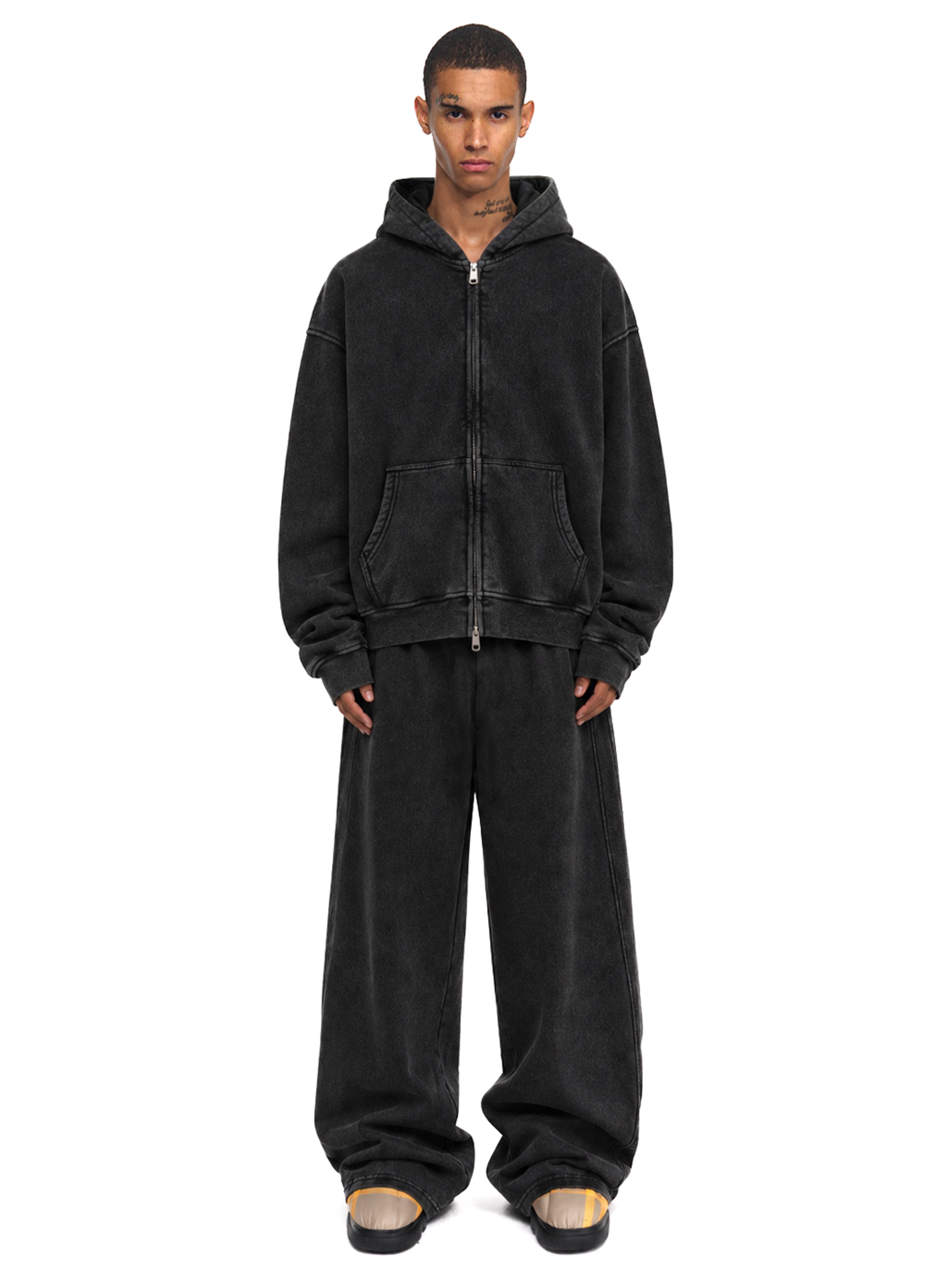 Man posing in a charcoal black oversized streetwear zip-up hoodie and loose fit joggers.