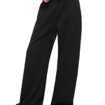 Profilansicht von der Seite eines Modells in den schwarzen weitbeinigen Jogginghosen von FDR Studios, die den fließenden Fall und die bequeme, übergroße Silhouette des Lyocell-Mischgewebedesigns zeigt.