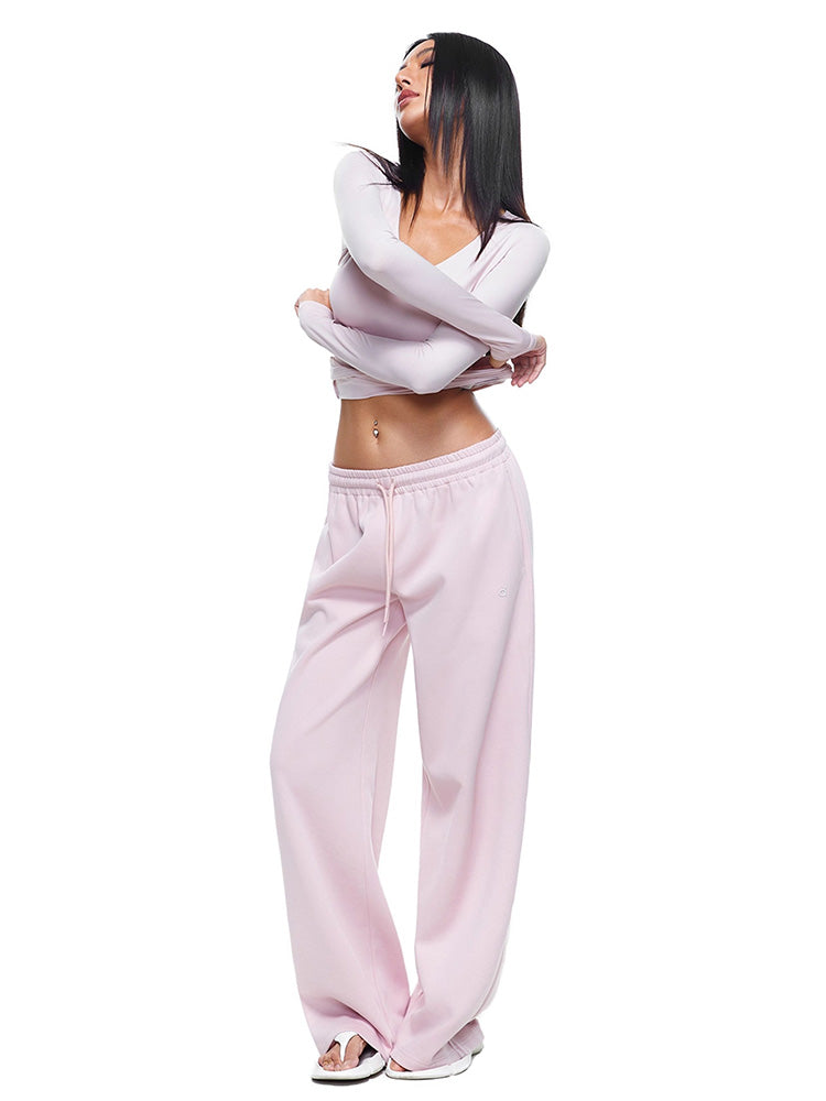 Full-body shot of a model wearing soft pink wide-leg sweatpants and matching long-sleeve top, demonstrating a feminine and stylish interpretation of women's comfortable loungewear.