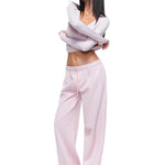 Full-body shot of a model wearing soft pink wide-leg sweatpants and matching long-sleeve top, demonstrating a feminine and stylish interpretation of women's comfortable loungewear.