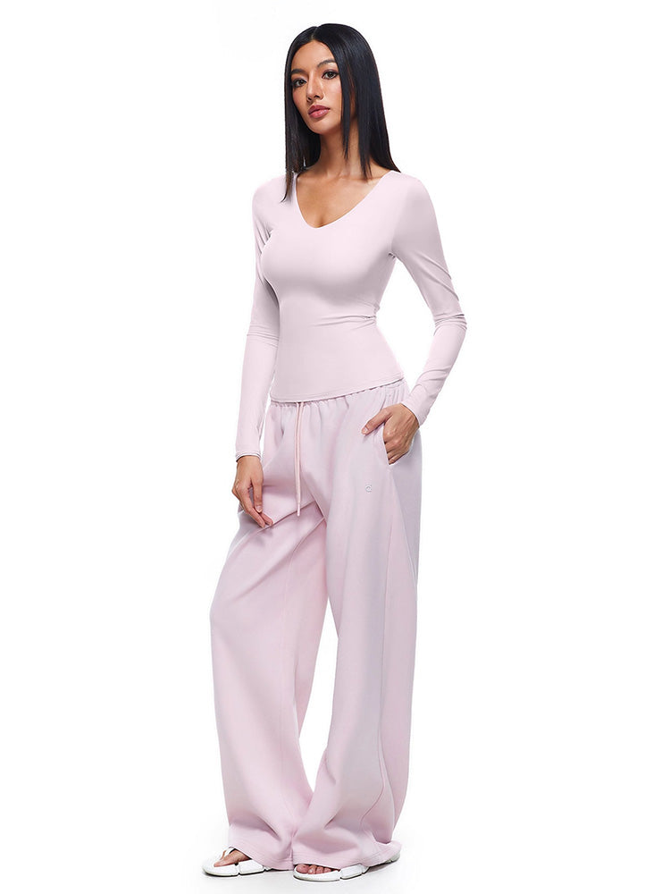 Full-body shot of a model wearing soft pink wide-leg sweatpants and matching long-sleeve top, demonstrating a feminine and stylish interpretation of women's comfortable loungewear.
