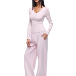 Full-body shot of a model wearing soft pink wide-leg sweatpants and matching long-sleeve top, demonstrating a feminine and stylish interpretation of women's comfortable loungewear.