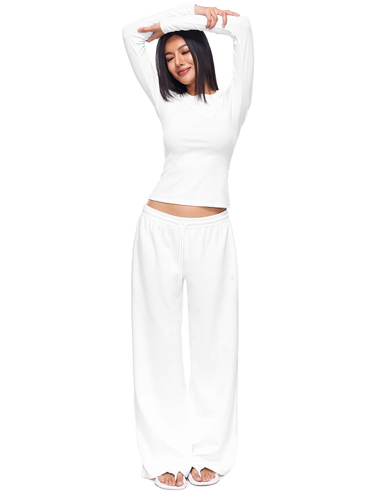 Full-body shot of a model wearing crisp white wide-leg sweatpants and matching long-sleeve top, illustrating a clean, minimal loungewear set with a relaxed, premium feel.