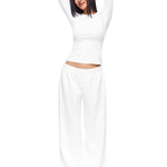 Full-body shot of a model wearing crisp white wide-leg sweatpants and matching long-sleeve top, illustrating a clean, minimal loungewear set with a relaxed, premium feel.
