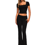 Full front view of a model wearing a black ribbed 2-piece set with lace trim and flare pants.