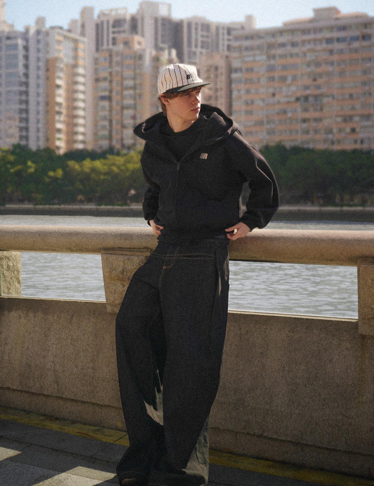 Model posing in FDR Studios oversized black zip-up hoodie, industrial high-street style urban background