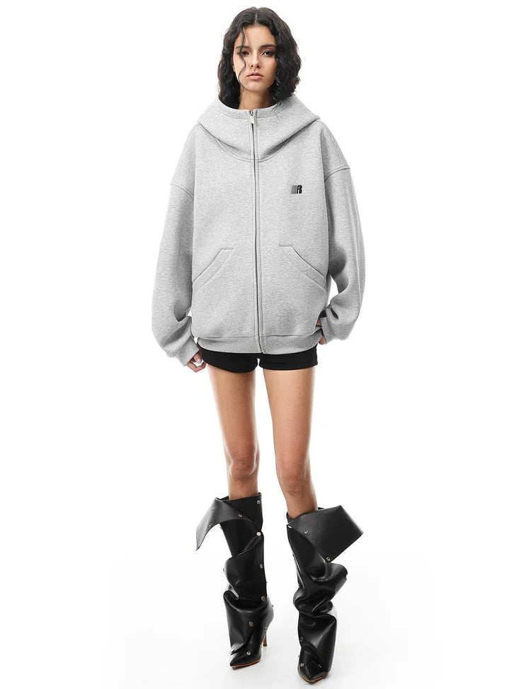 Model in grey oversized high-neck zip hoodie with chunky boots, industrial edgy aesthetic.