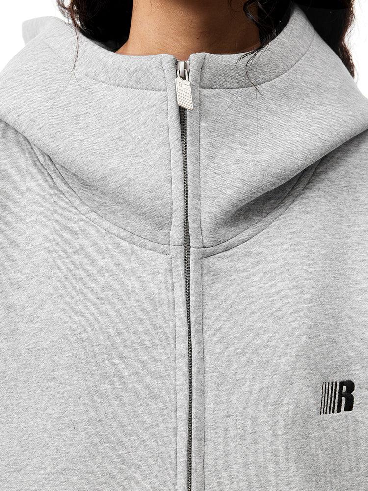 Close-up of grey hoodie neckline, highlighting the high-neck zipper and subtle metal logo detail.
