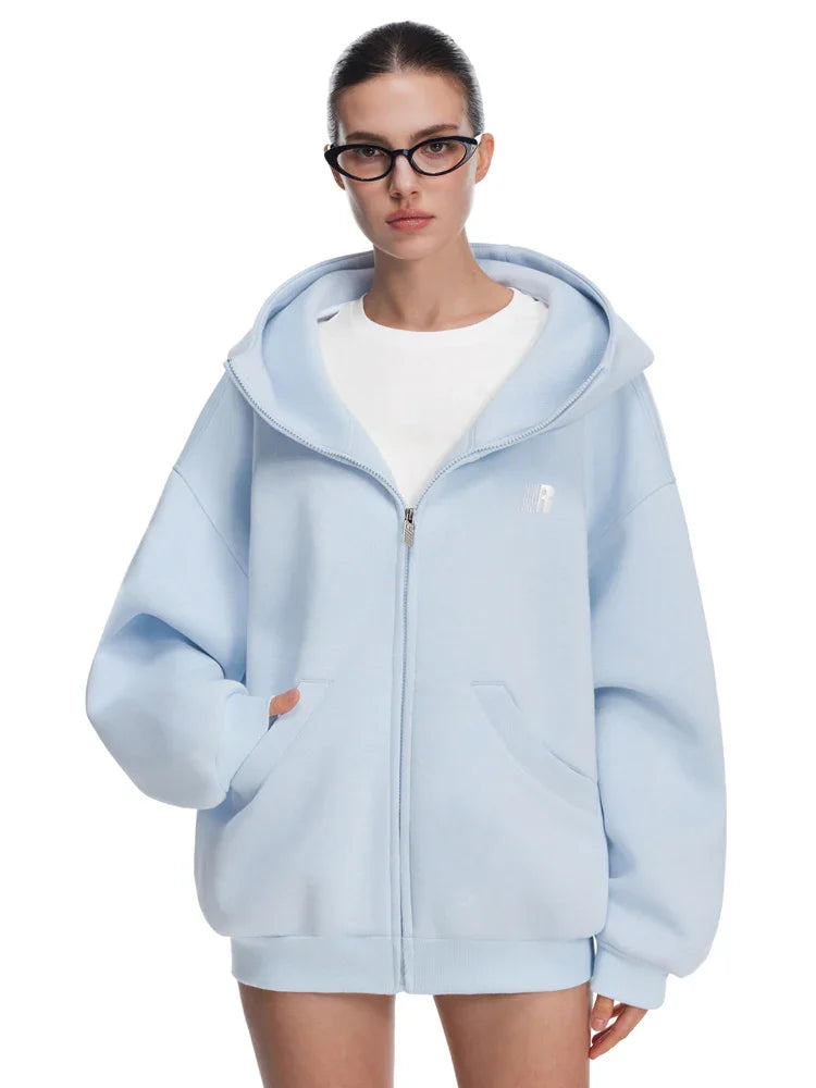 Model in light blue oversized zip-up hoodie, featuring minimalist silhouette and fresh pastel tones.