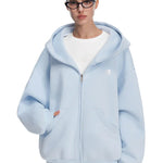 Model in light blue oversized zip-up hoodie, featuring minimalist silhouette and fresh pastel tones.