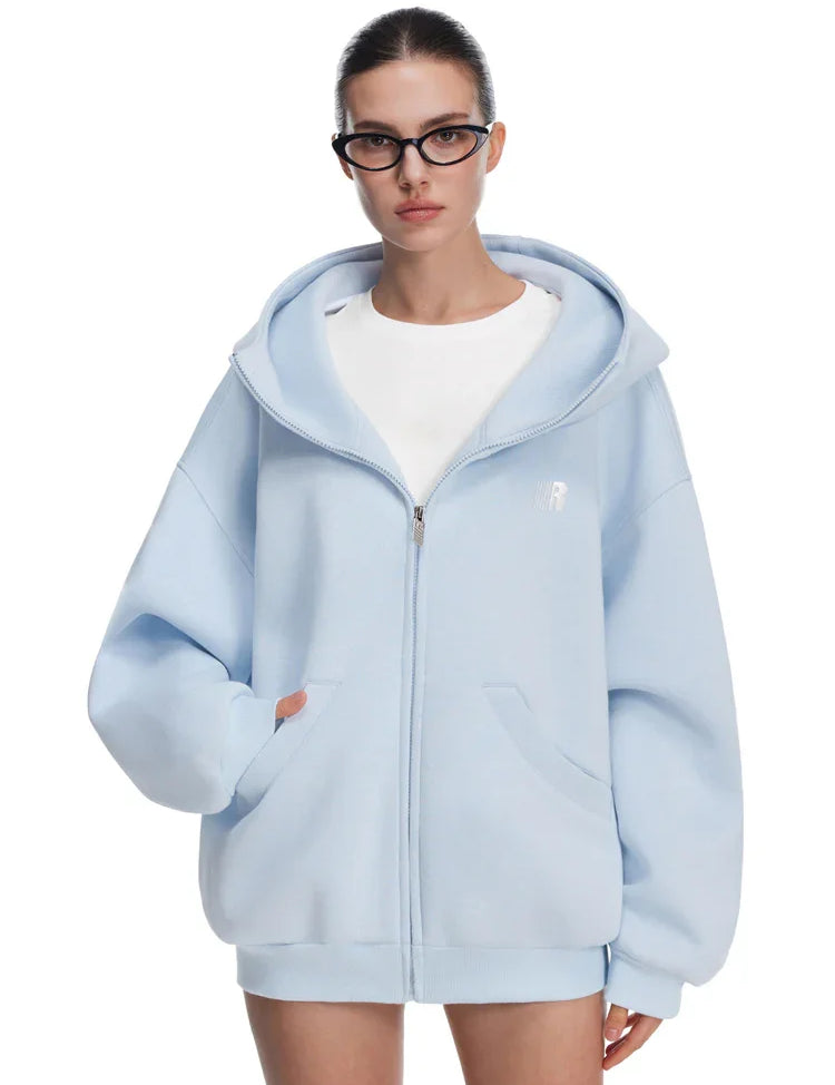 Model in light blue oversized zip-up hoodie, featuring minimalist silhouette and fresh pastel tones.
