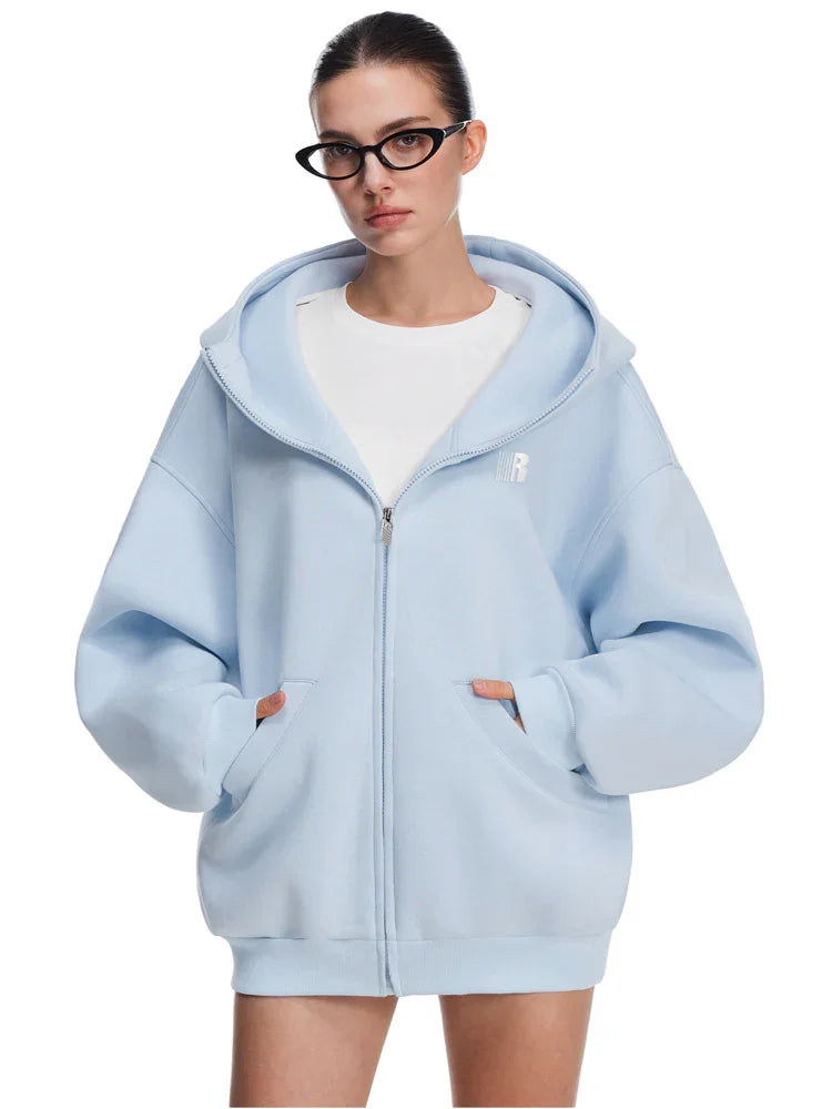 Front view of model in sky blue baggy hoodie with kangaroo pockets, clean modern streetwear.