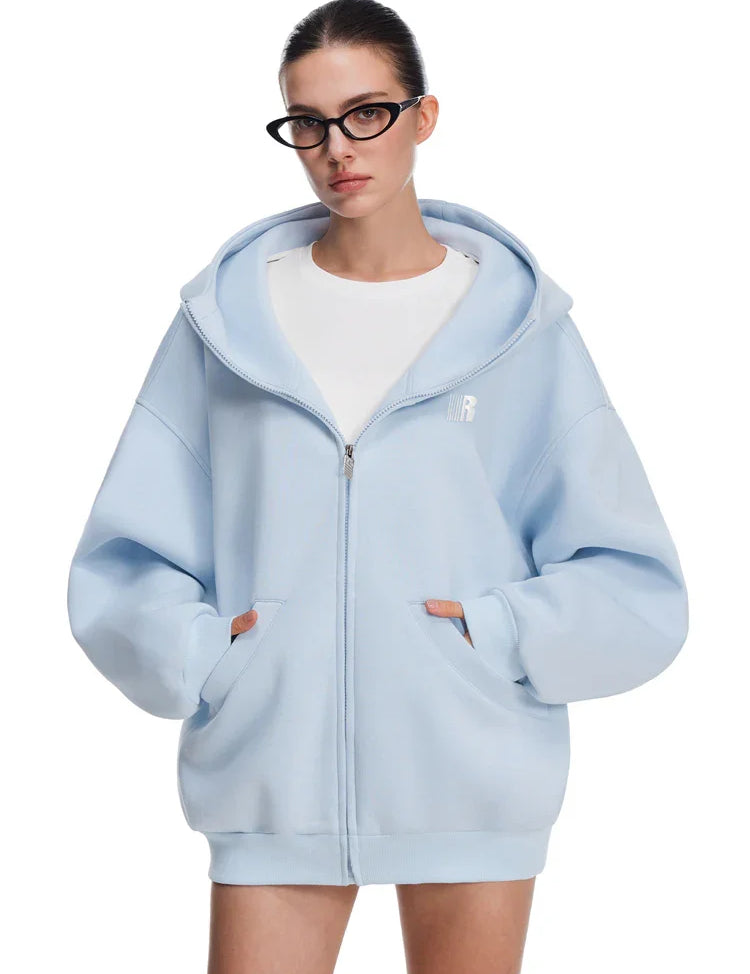 Front view of model in sky blue baggy hoodie with kangaroo pockets, clean modern streetwear.