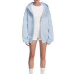 Full body view of model styling a light blue hoodie with white base layer, minimalist high-street look.