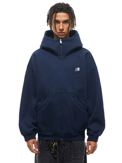 Front view of male model in navy blue oversized zip hoodie, urban techwear aesthetic.