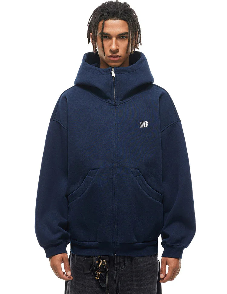 Front view of male model in navy blue oversized zip hoodie, urban techwear aesthetic.