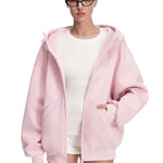 Model in pastel pink hoodie with hands in pockets, showing smooth fabric texture and subtle branding.