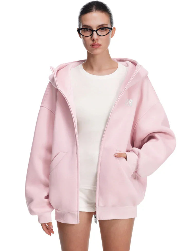 Model in pastel pink hoodie with hands in pockets, showing smooth fabric texture and subtle branding.